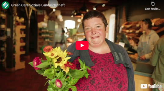 Eine Person mit Blumen davor der youtubeplaybutton