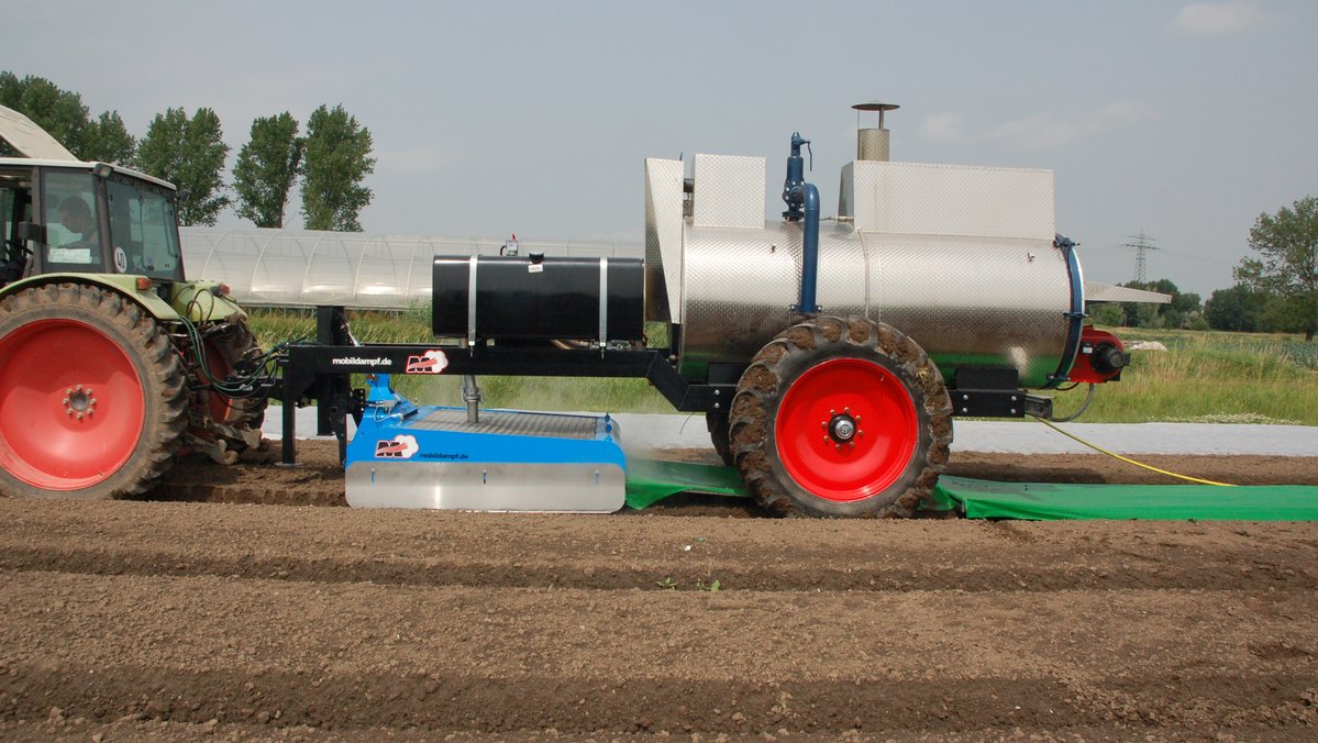Ein Gerät zur thermischen Bodenbehandlung wird im Feld eingesetzt und von einem Trecker gezogen.