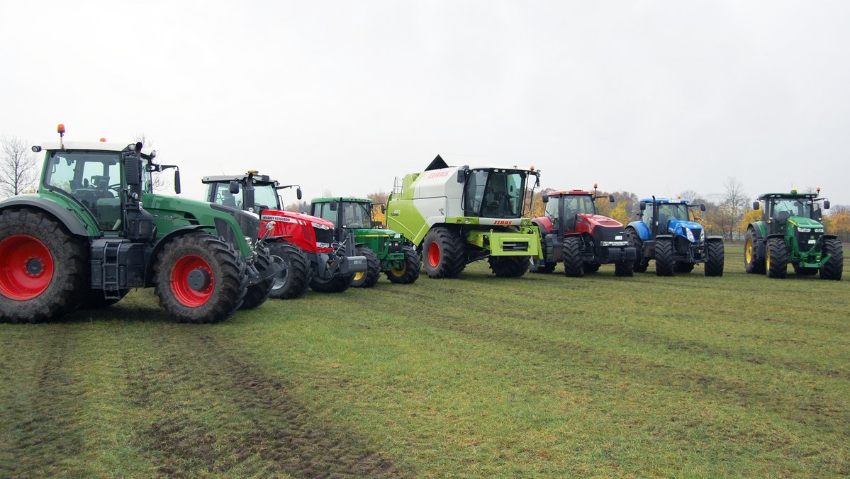 Eine Vielzahl von Landmaschinen steht in einer Reihe auf einem Feld.
